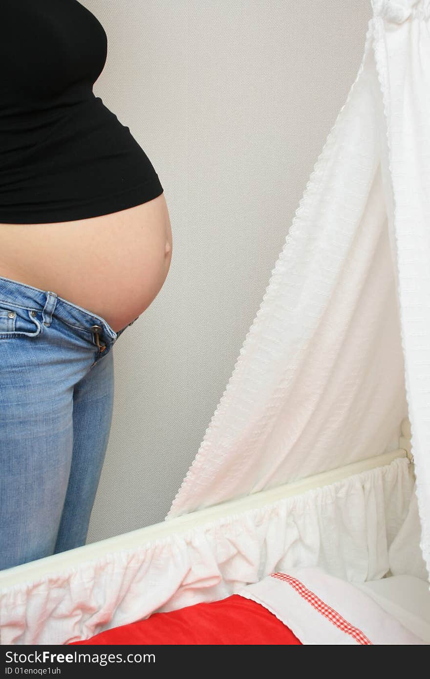 Pregnant woman standing next to a cradle. Pregnant woman standing next to a cradle