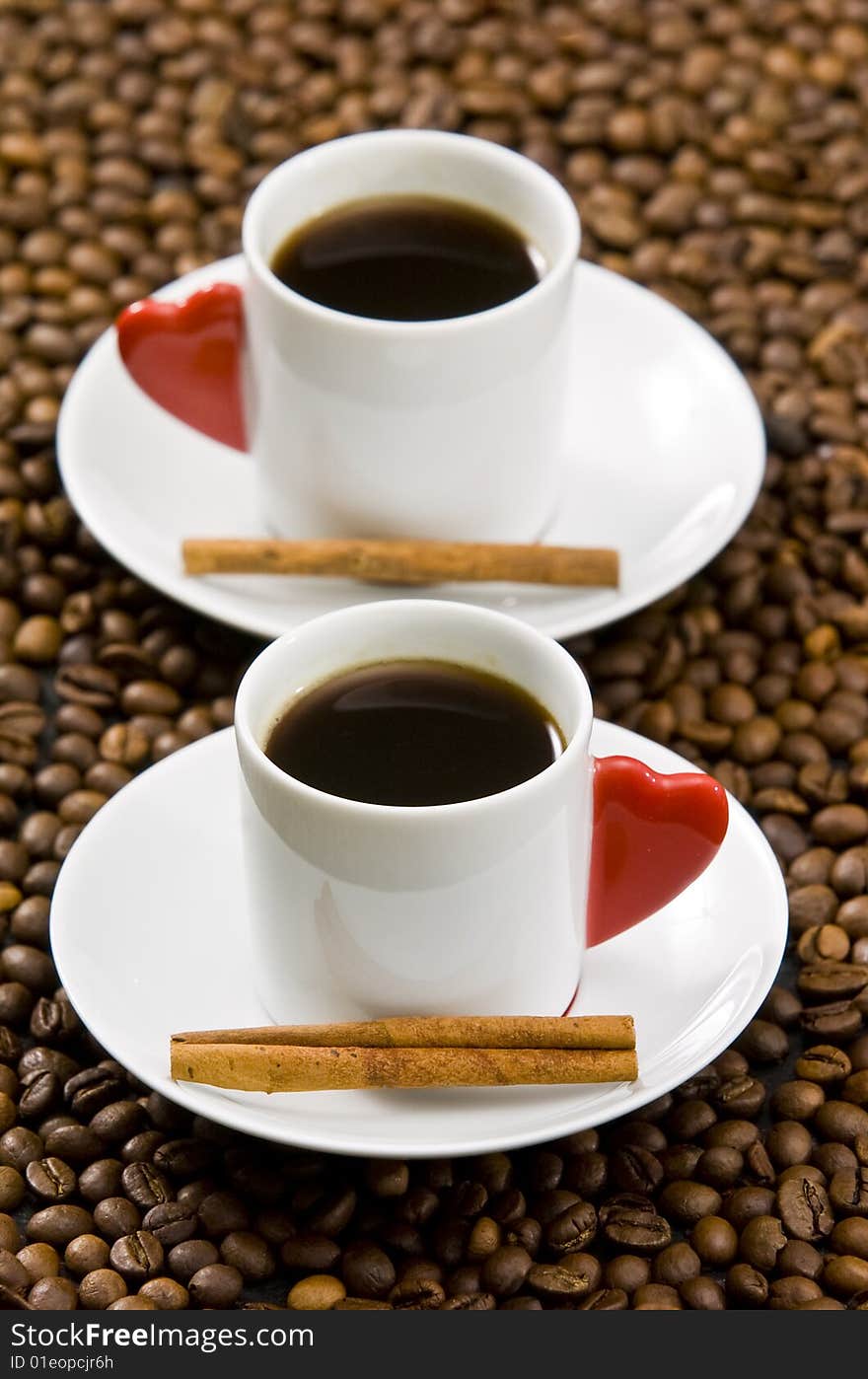 Espresso served on heart shaped cup on coffee beans