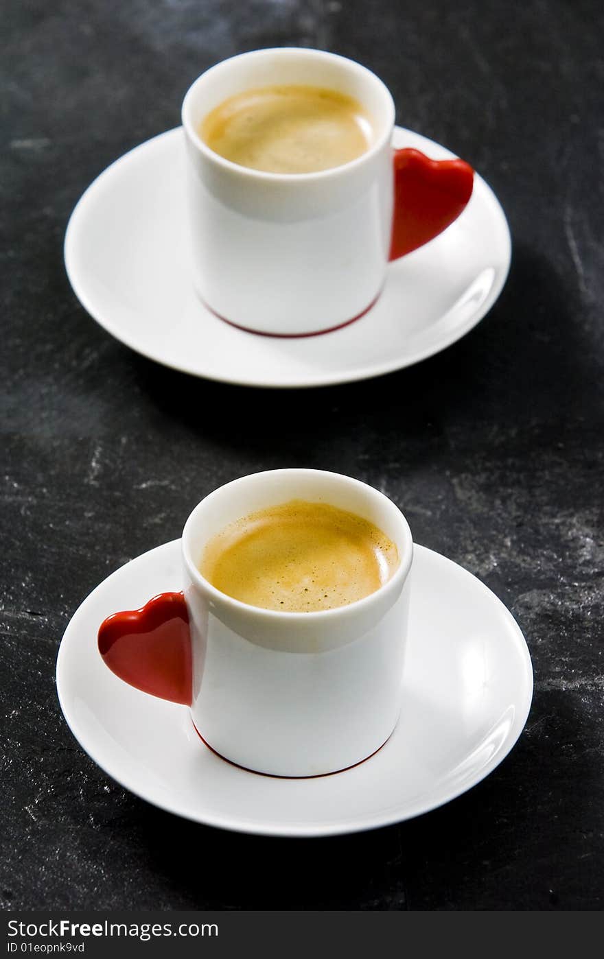 Espresso served on heart shaped cup on coffee beans