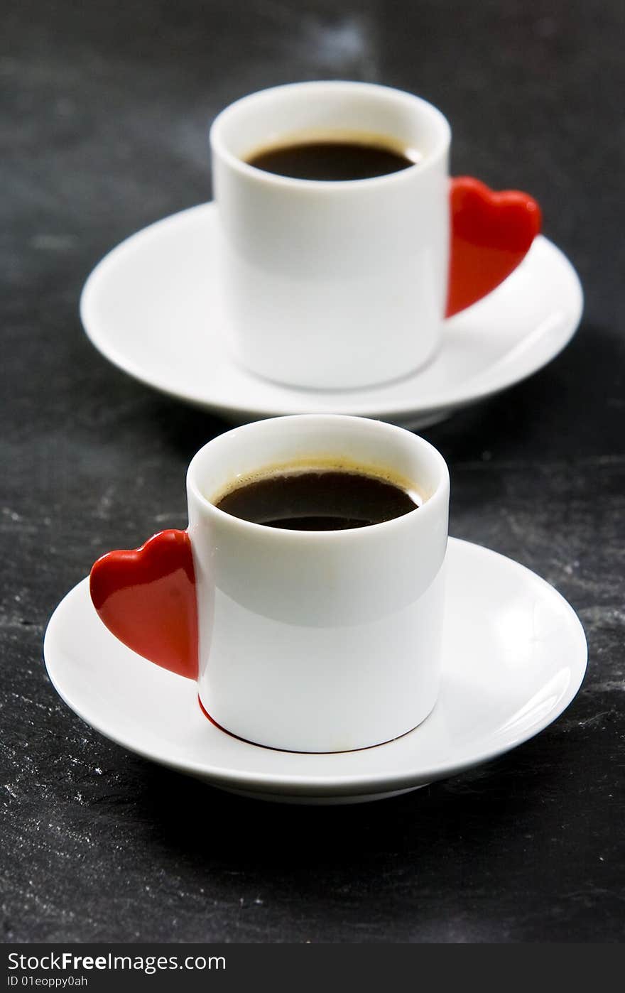 Espresso served on heart shaped cup on coffee beans