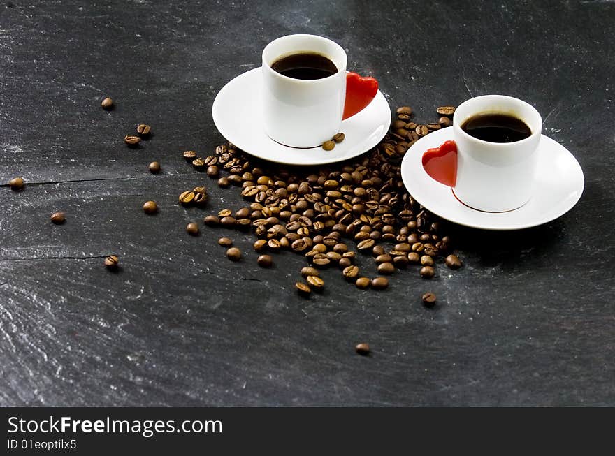 Espresso served on heart shaped cup on coffee beans