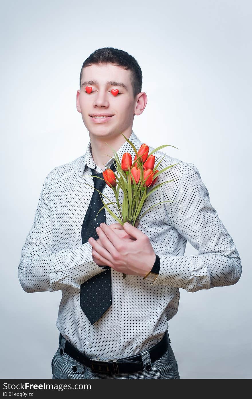 Romantic man with tulips and heart-shaped candies over his eyes