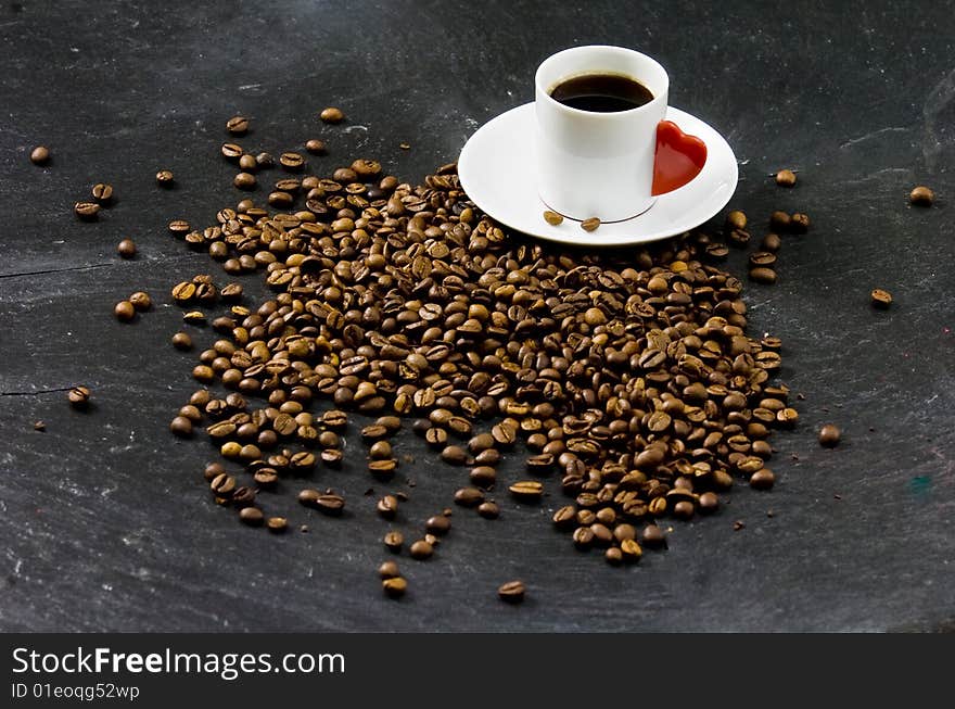 Espresso served on heart shaped cup on coffee beans