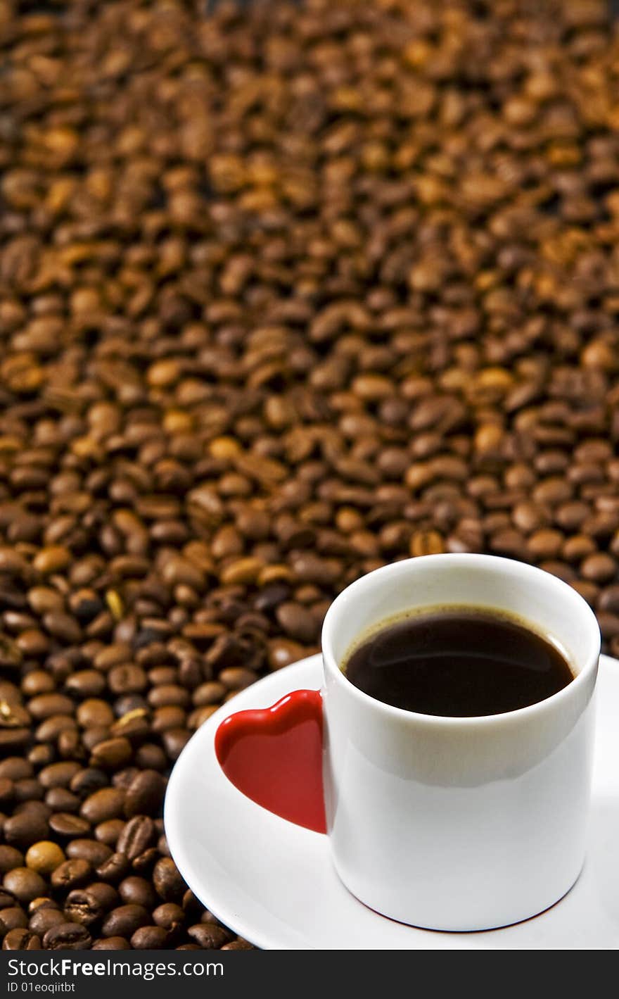 Espresso served on heart shaped cup on coffee beans