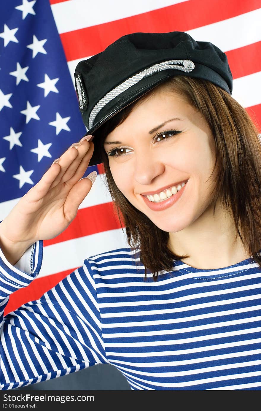 Happy beautiful young sailor stands near the American flag and salutes