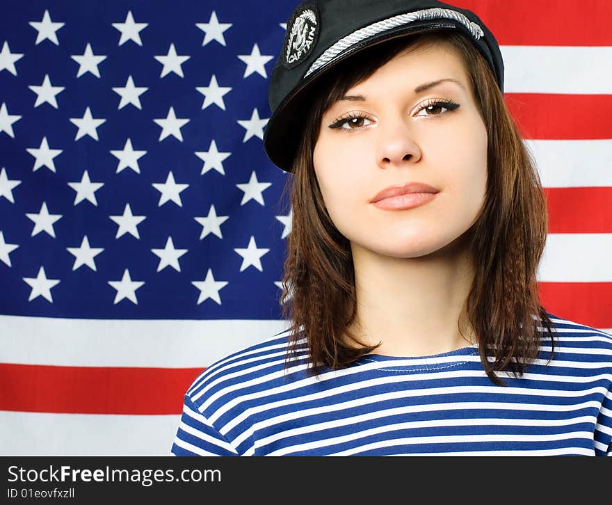 Beautiful young confident sailor standing near the American flag. Beautiful young confident sailor standing near the American flag