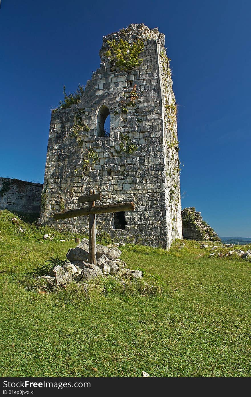 Ancient tower and a cross on the top of the mountain