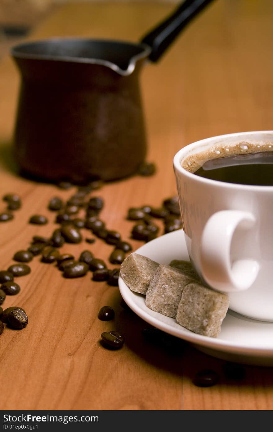 Cup of coffee, caffee-maker, sugar and beans on wooden table. Cup of coffee, caffee-maker, sugar and beans on wooden table