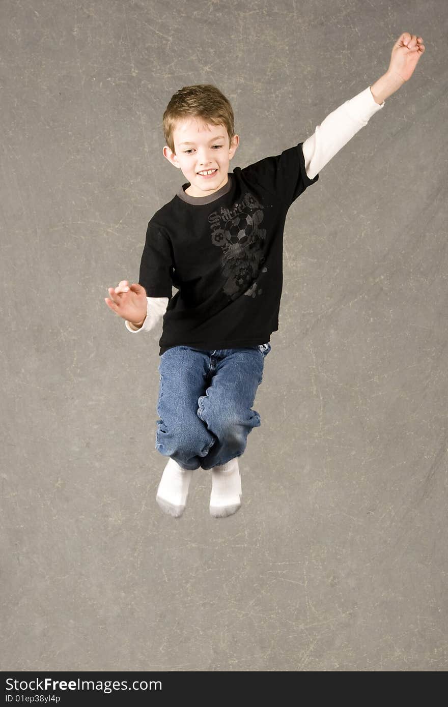 Little boy leaping into air over gray background. Little boy leaping into air over gray background