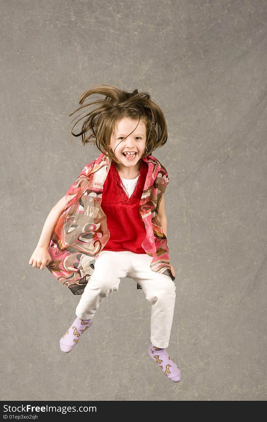 Little girl having fun leaping into air, over gray background. Little girl having fun leaping into air, over gray background