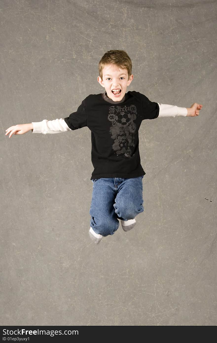 Little boy leaping in air, over gray background