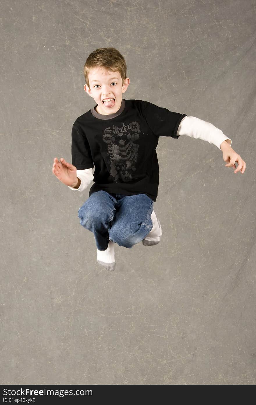 Little boy jumping into air over gray background