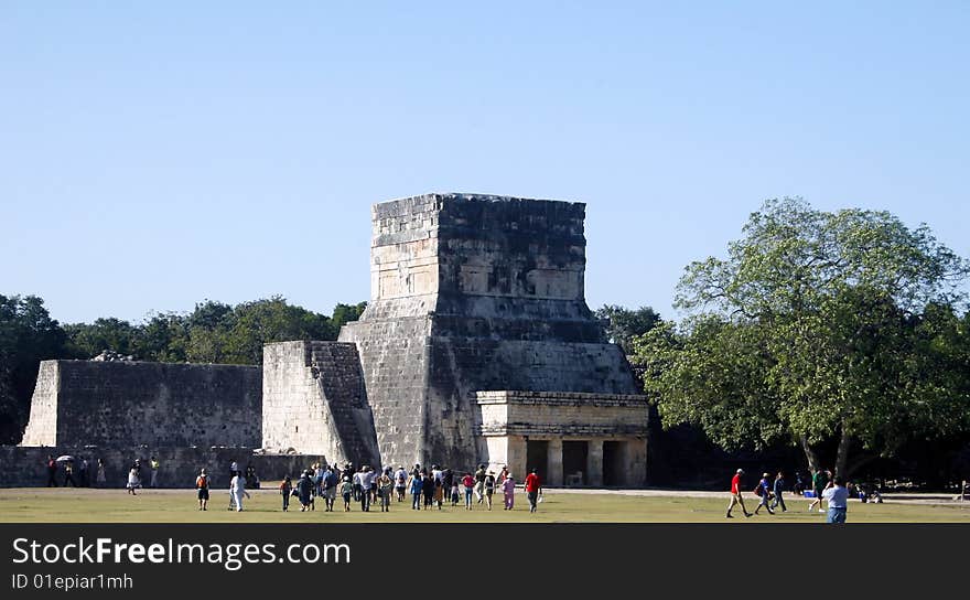 Toruists are walking about a mayan religous ruin. Toruists are walking about a mayan religous ruin