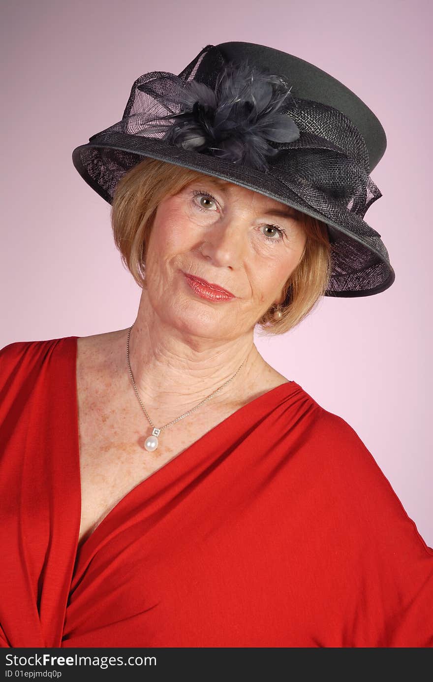 Portrait of very attractive older woman wearing black hat and red dress. Portrait of very attractive older woman wearing black hat and red dress