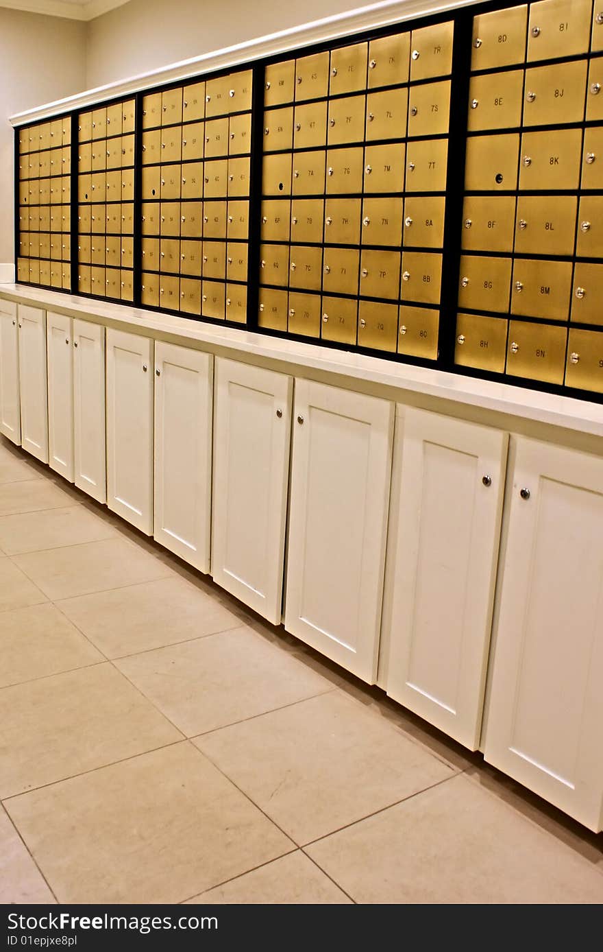 Rows of indoor brass mailboxes above locked cabinets. Rows of indoor brass mailboxes above locked cabinets