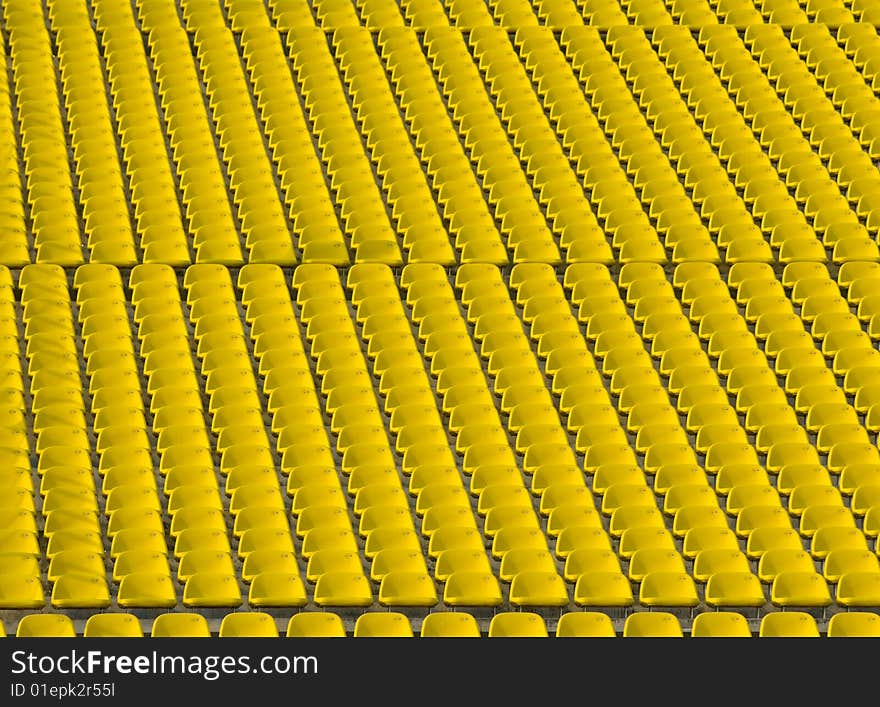 Rows and rows of yellow stadium seats on an incline creating an urban abstract