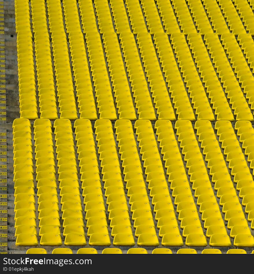 Rows and rows of yellow stadium seats on an incline creating an urban abstract