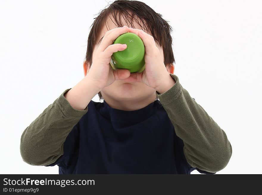 Small boy drinking from green plastic cup.