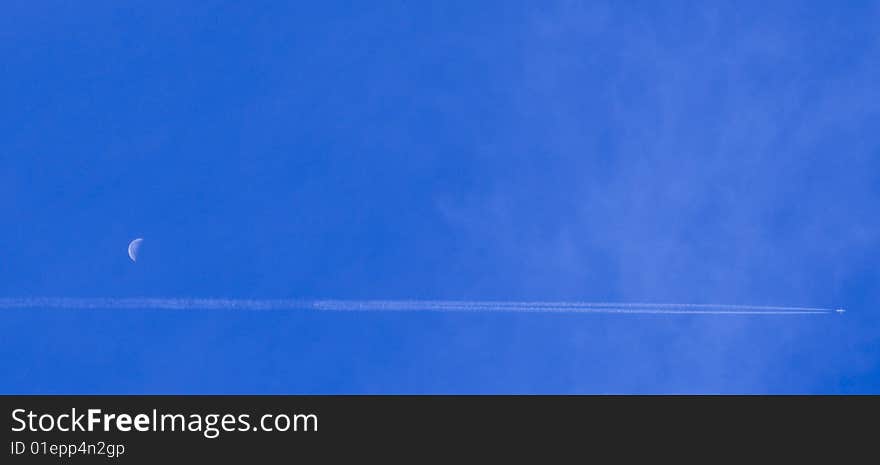 Plane flying through a blue sky with a half moon. Plane flying through a blue sky with a half moon