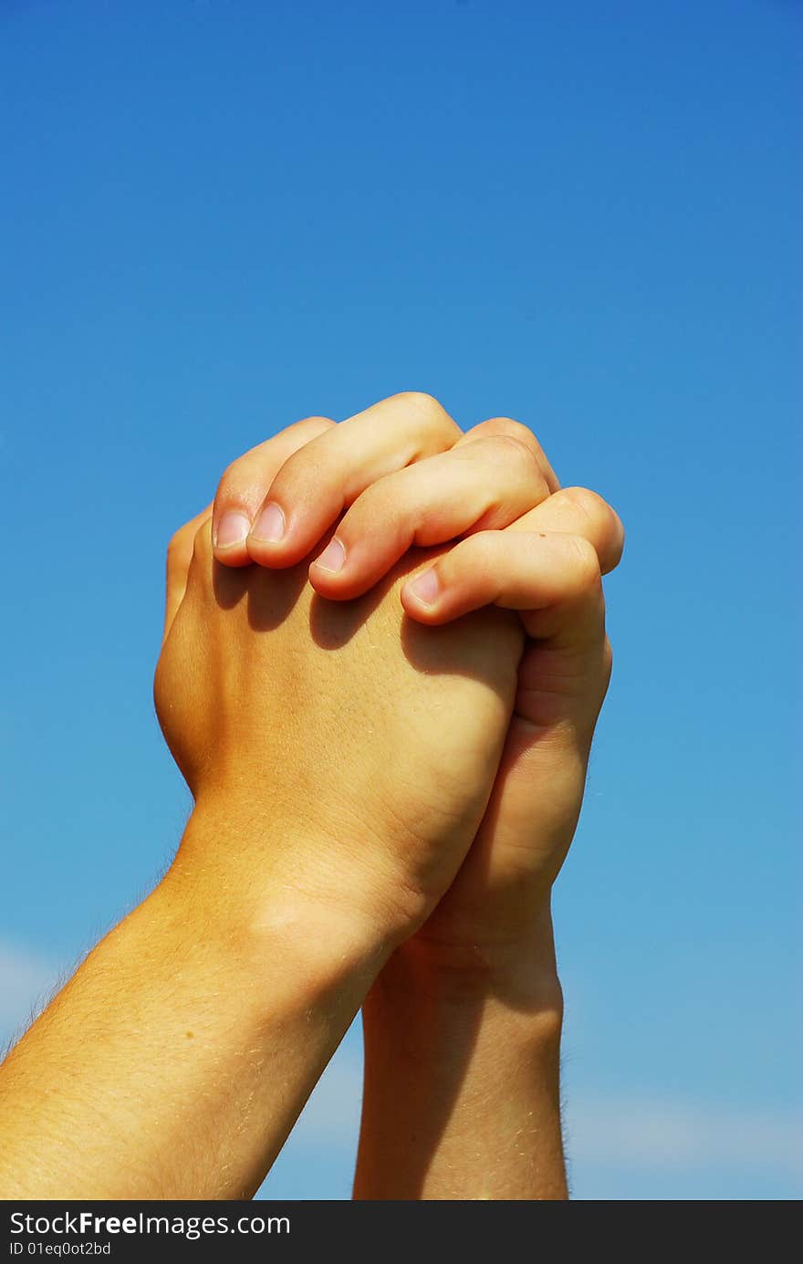 Hands in prayer gesture on sky