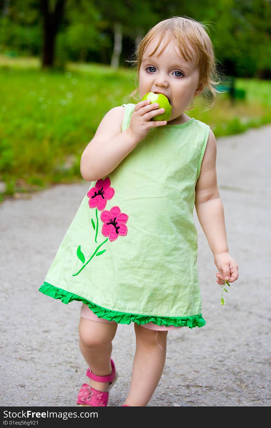 The girl eats, thinking, outdoors