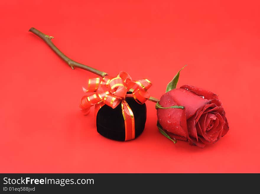 Red rose and black gift box on the red background. Red rose and black gift box on the red background.