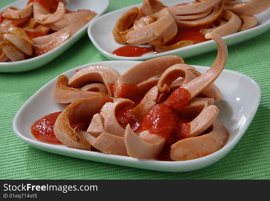 Fresh sausages poured with ketchup on plate