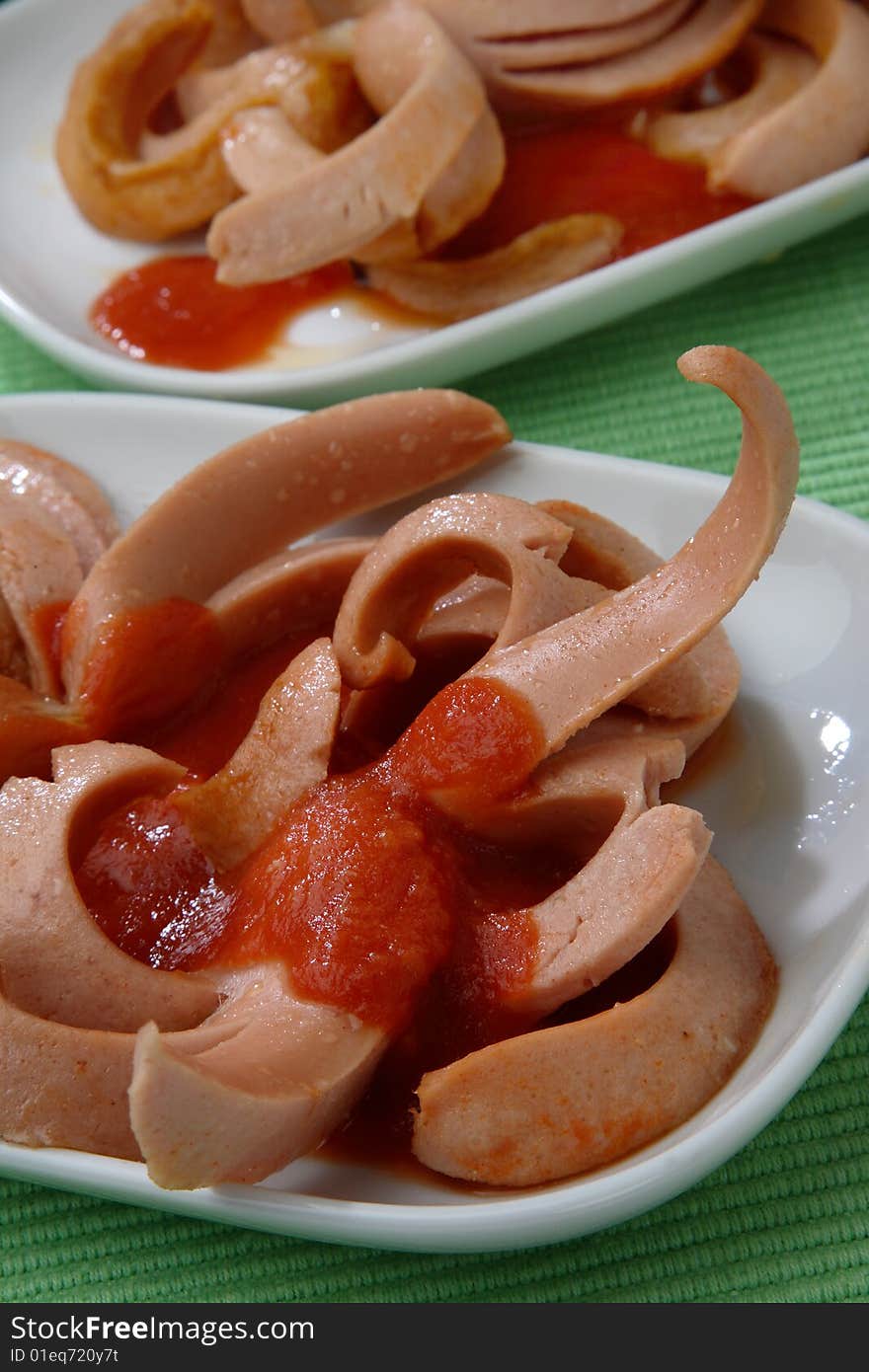 Fresh sausages poured with ketchup on plate