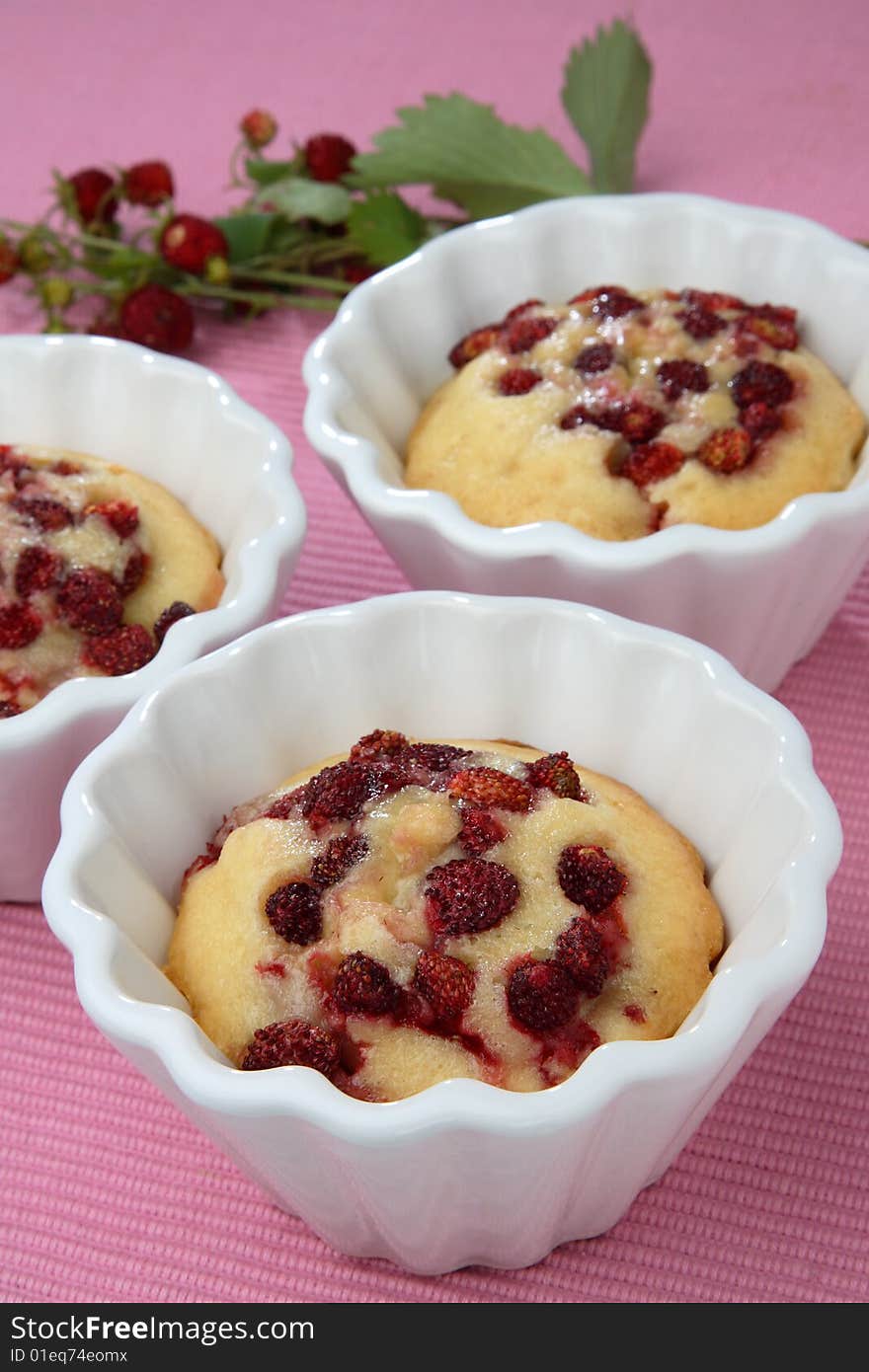 Strawberry muffins in white muffin bowls on table