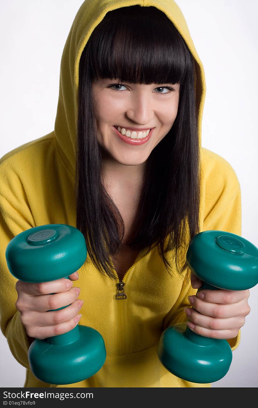 Smiling young girl with two green dumbbells