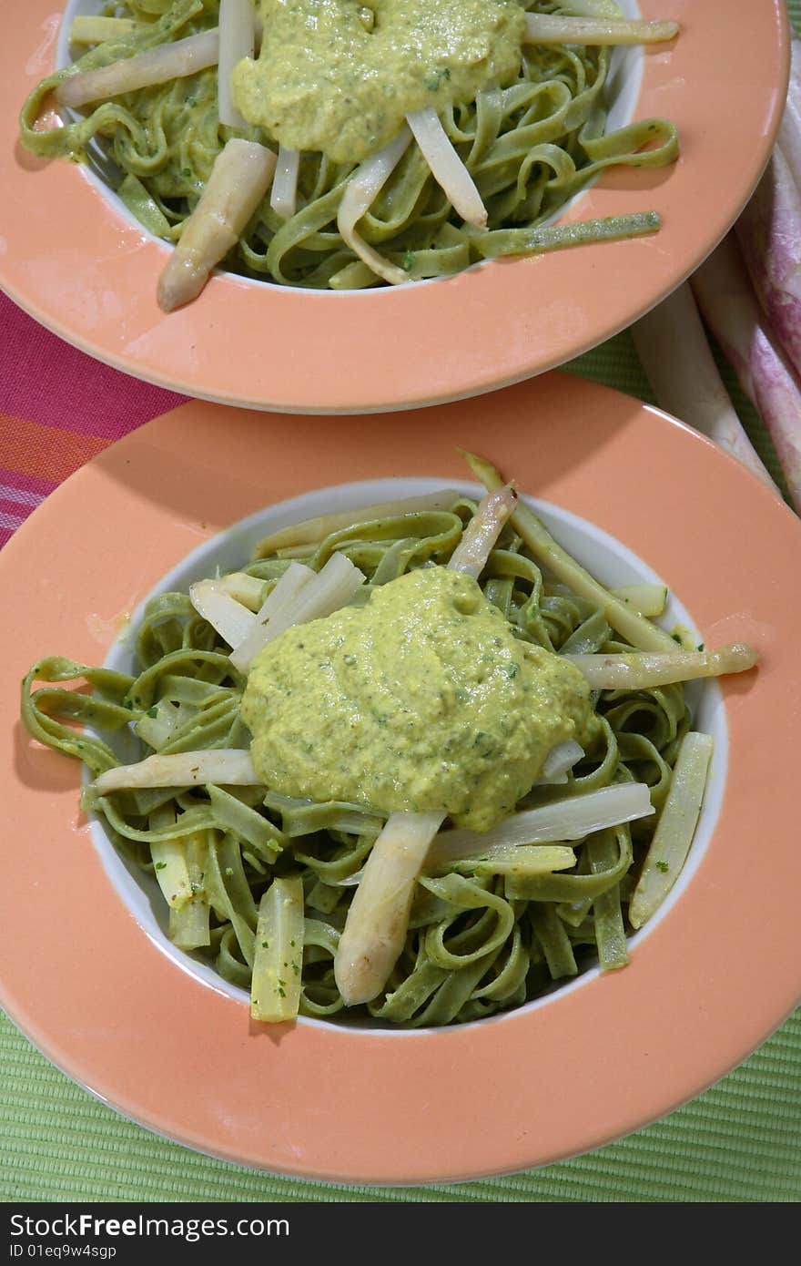 Green noodles with white asparagus and sauce on plate