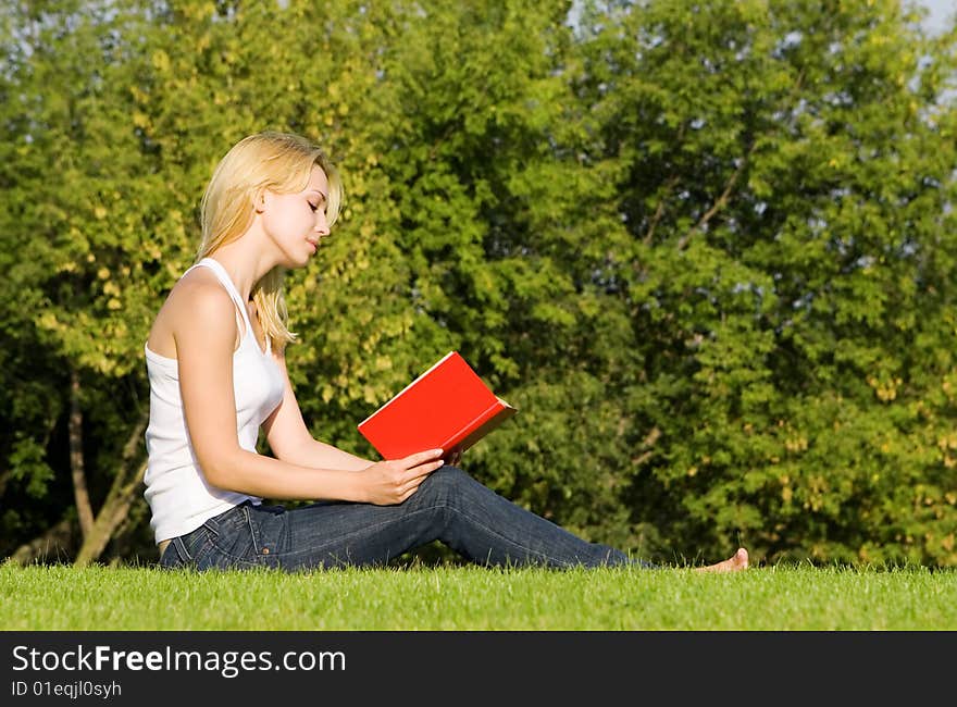 Young blonde reads book in the park