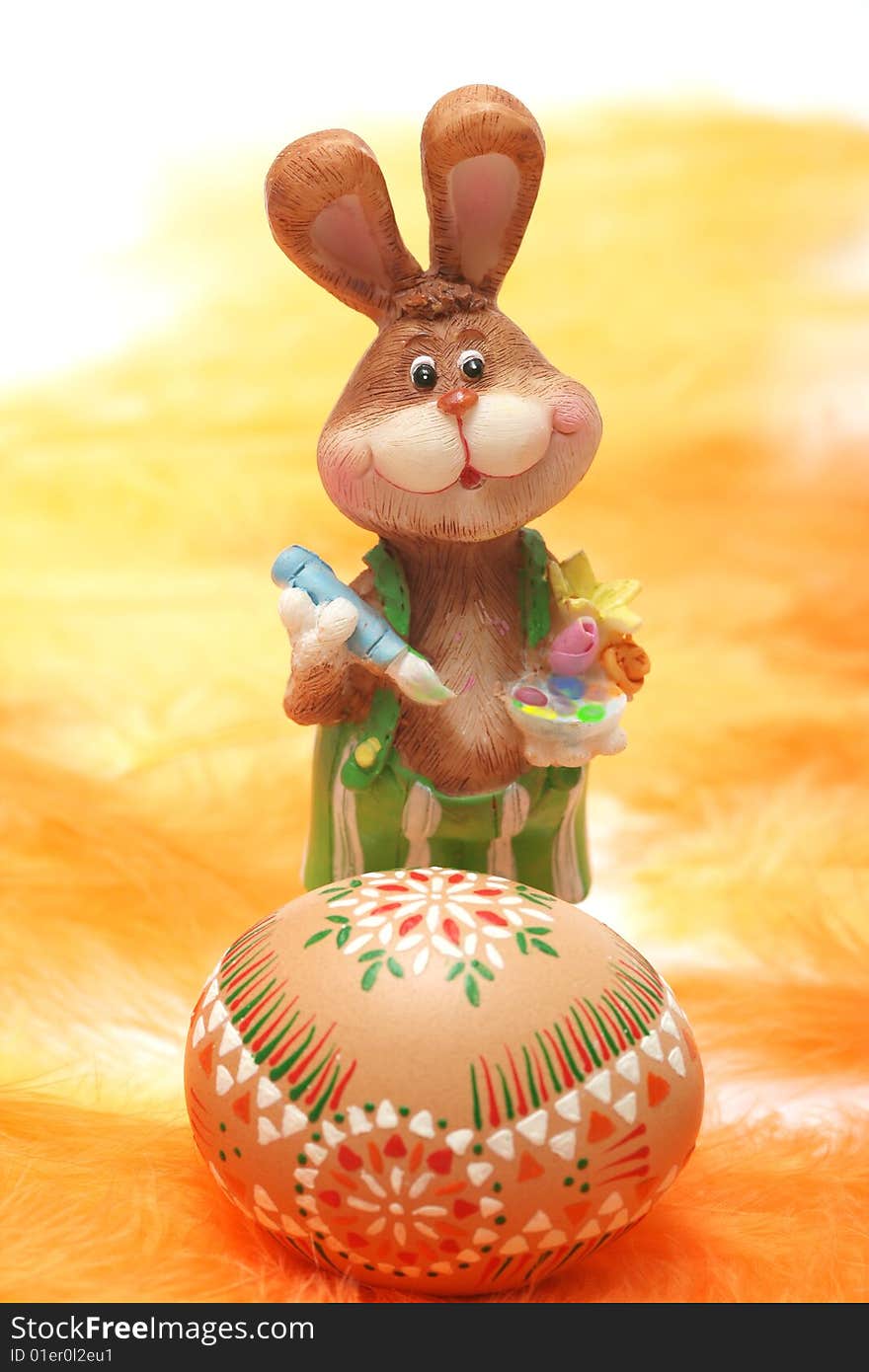 Easter bunny with easter egg on orange and yellow feathers