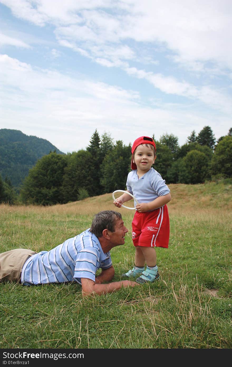 Portrait of a smiling toddler and his uncle. Baby tries to hang a circle on the head of his uncle. Taken outdoors. Portrait of a smiling toddler and his uncle. Baby tries to hang a circle on the head of his uncle. Taken outdoors.