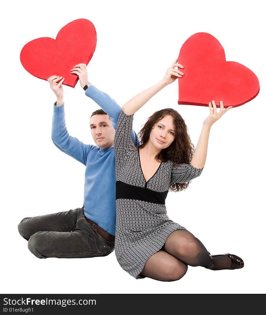 Couple sitting holding red hearts  isolated over white background