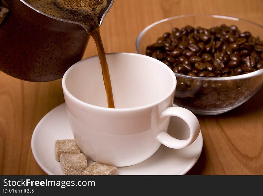 Cup of coffee, sugar and beans in glass bowl on wooden table