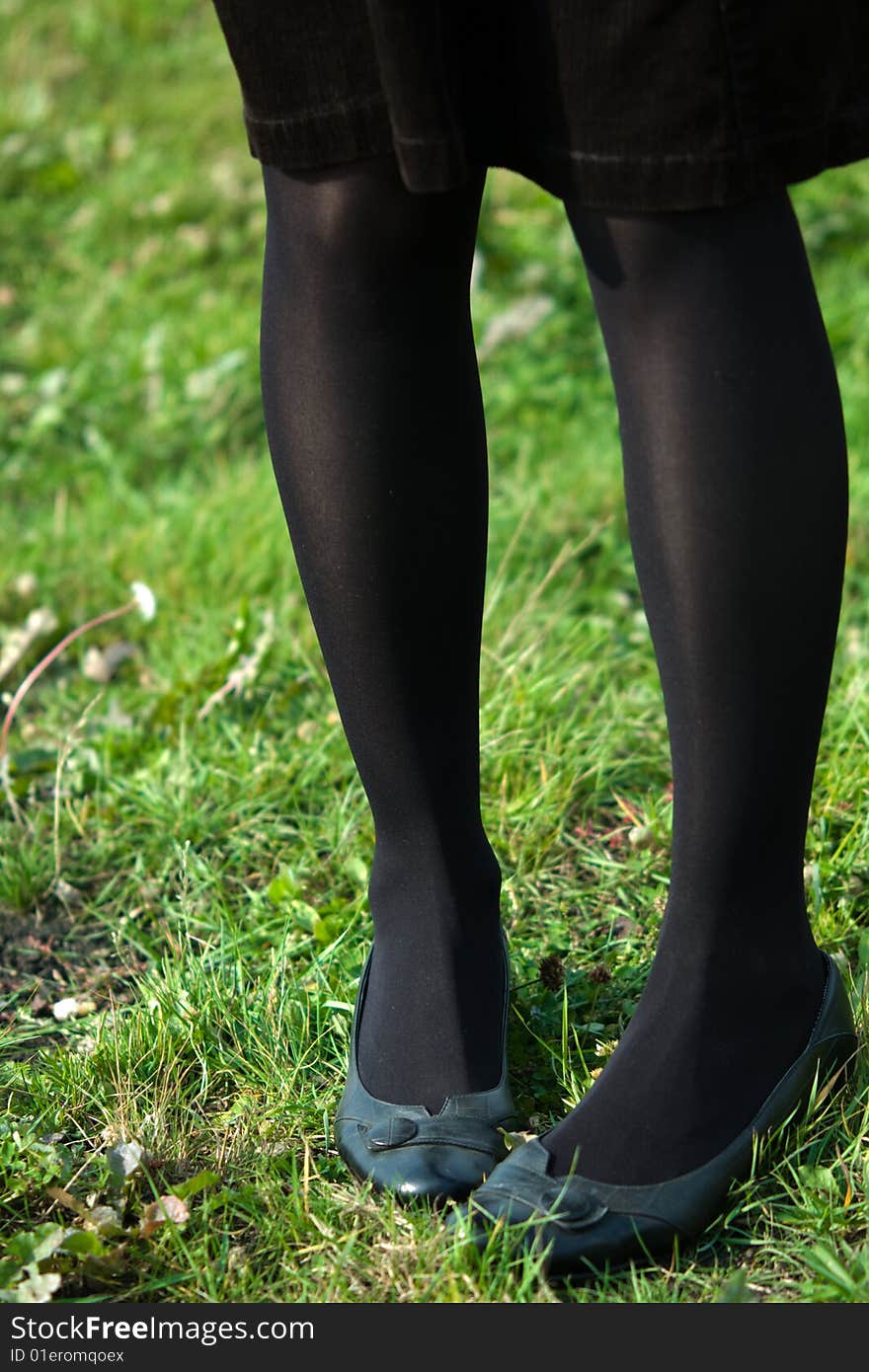 Slender legs in funny position on green grass background