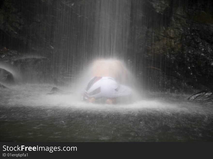 A young man gets a massage from a waterfall. A young man gets a massage from a waterfall