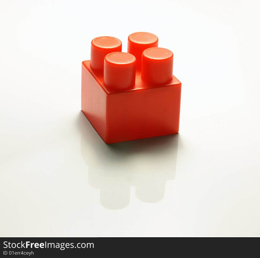 One red cube from the children's designer on a white background with a shade and reflexion