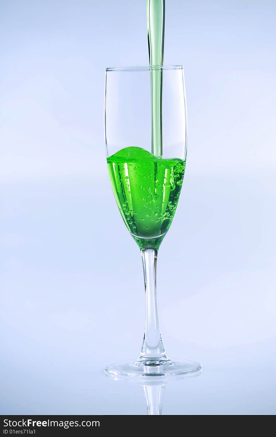 Green liquid drink being poured into wine glass