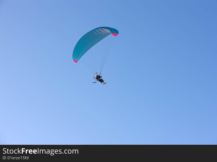 Paraplane flying, wide shot over blue sky