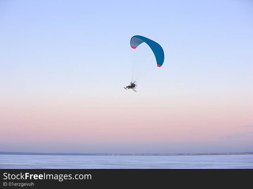 Paraplane flying, wide shot over blue sky