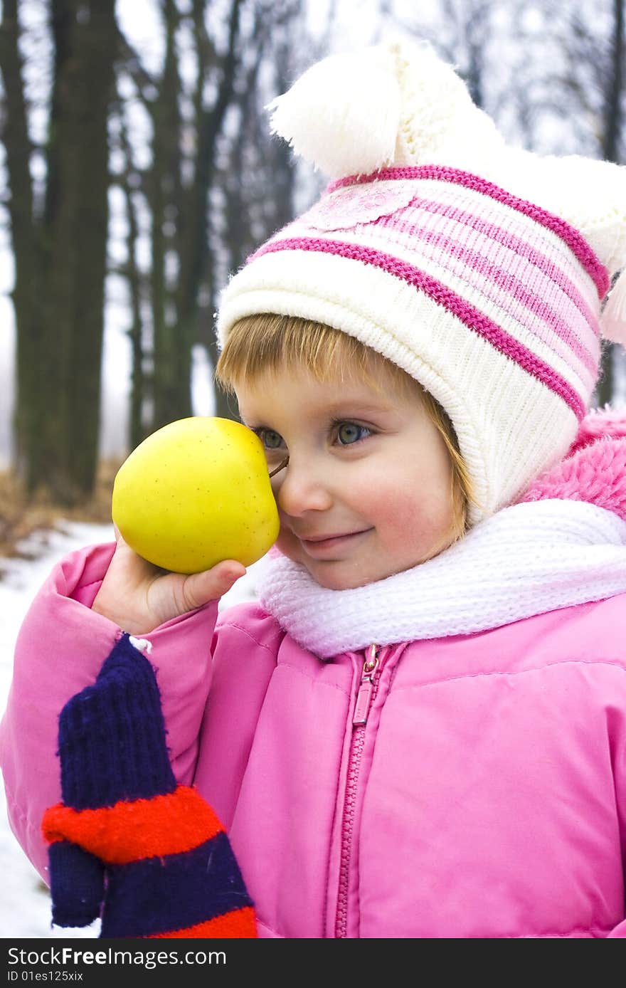 Baby and apple in pink jacket on the winter background