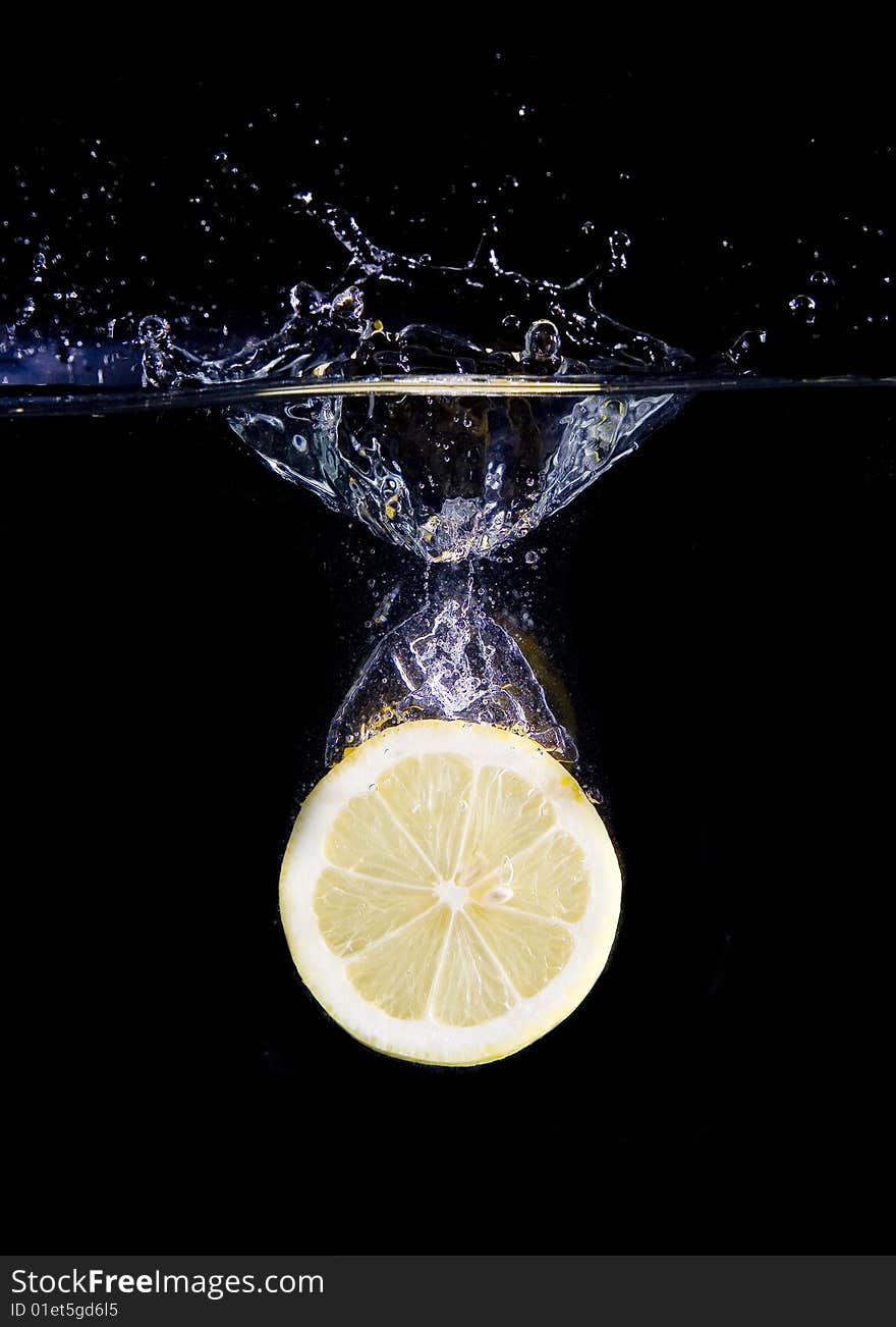 Lemon slice in water with bubbles on black ground. Lemon slice in water with bubbles on black ground