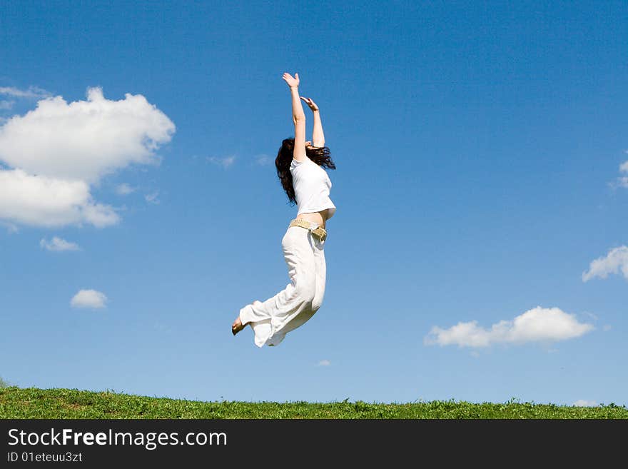 Happy young woman is jumping in green grass