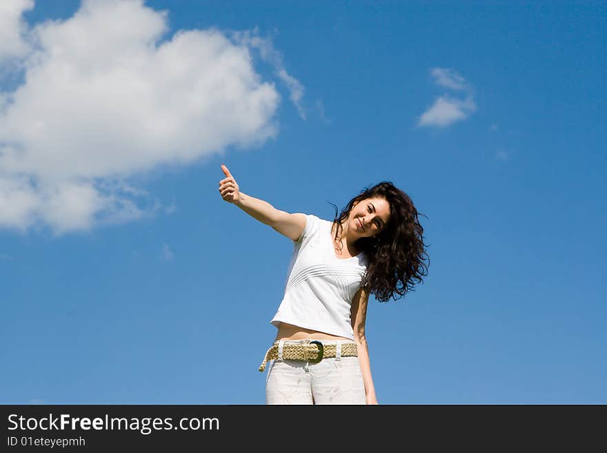 Young woman on a green meadow shows ok sign