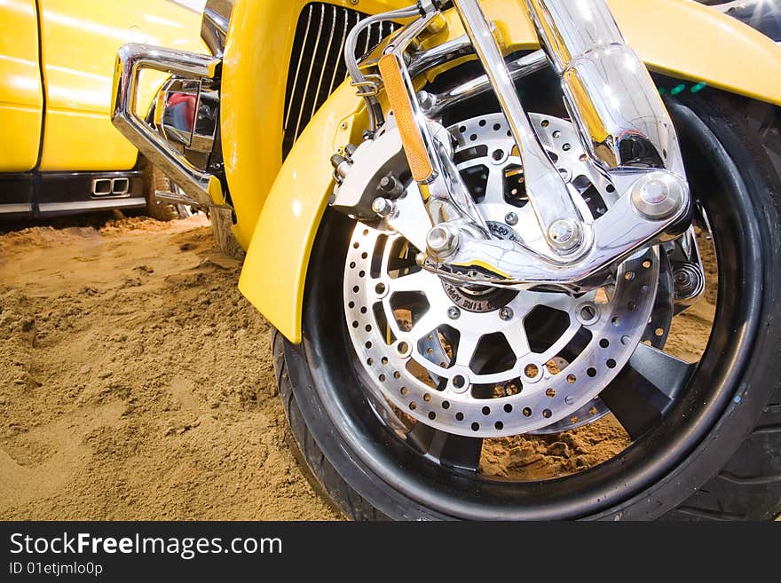 Part of yellow motorbike on the sand