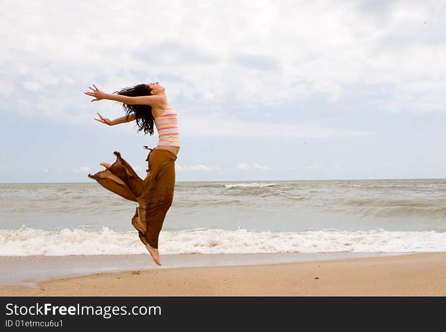 Happy young woman is jumping in beach. Happy young woman is jumping in beach