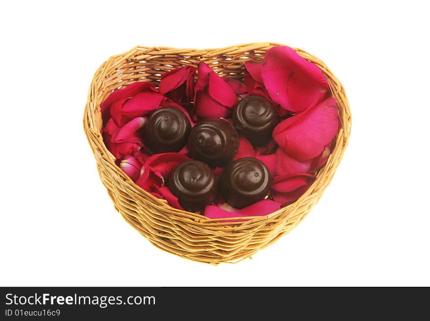 Red rose petals and liquer chocolates in a heart shaped basket. Red rose petals and liquer chocolates in a heart shaped basket