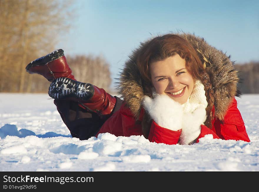 Girl lays on snow and touches the face mitten. Girl lays on snow and touches the face mitten